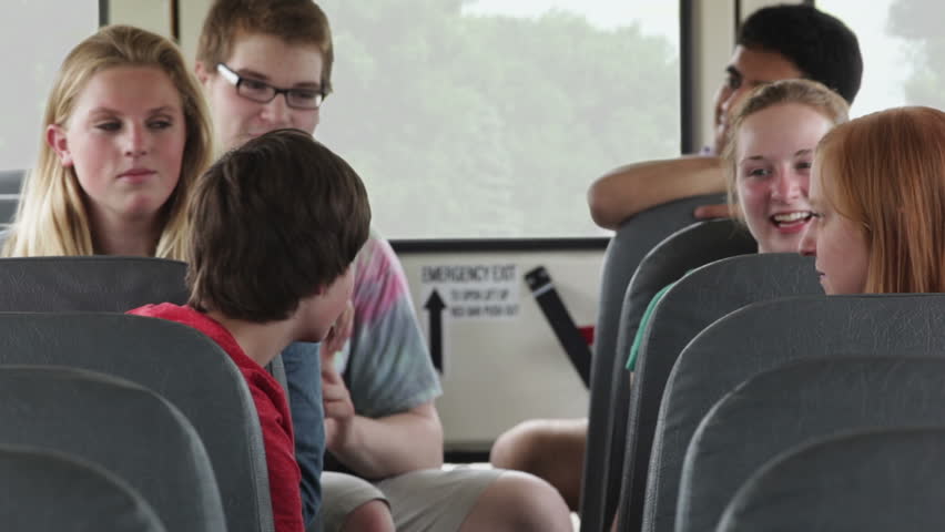 High School Kids Talking To Each Other While Riding A School Bus Stock