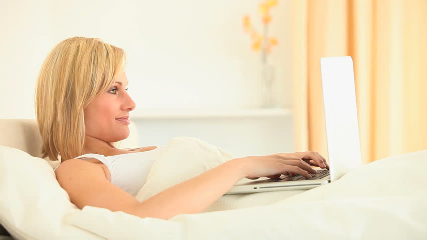 Blonde Using Laptop In Bedroom And Smiling At Camera Stock