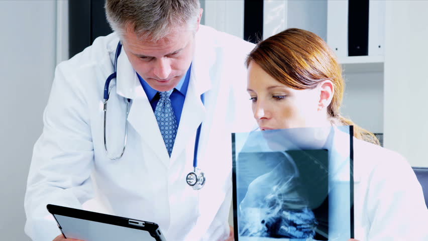 caucasian male female medical colleagues consulting over patient x ray results with computer screen shot - Epic Consultant caucasian male female medical colleagues consulting over patient x ray results with computer screen shot - Epic Consultant